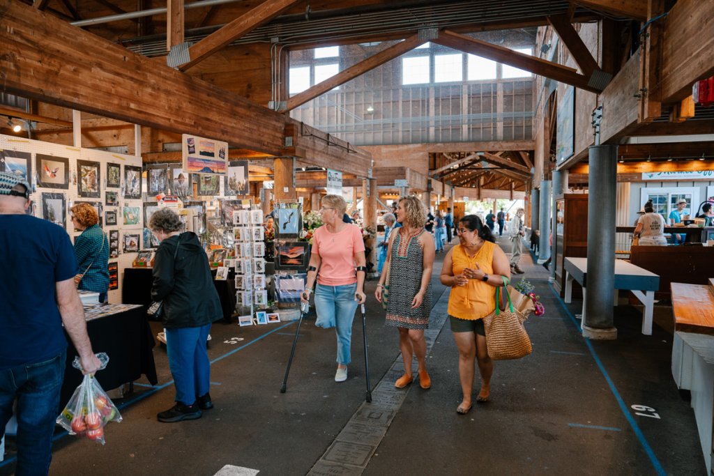 Three women walk through the interior of the Olympia Farmers Market.