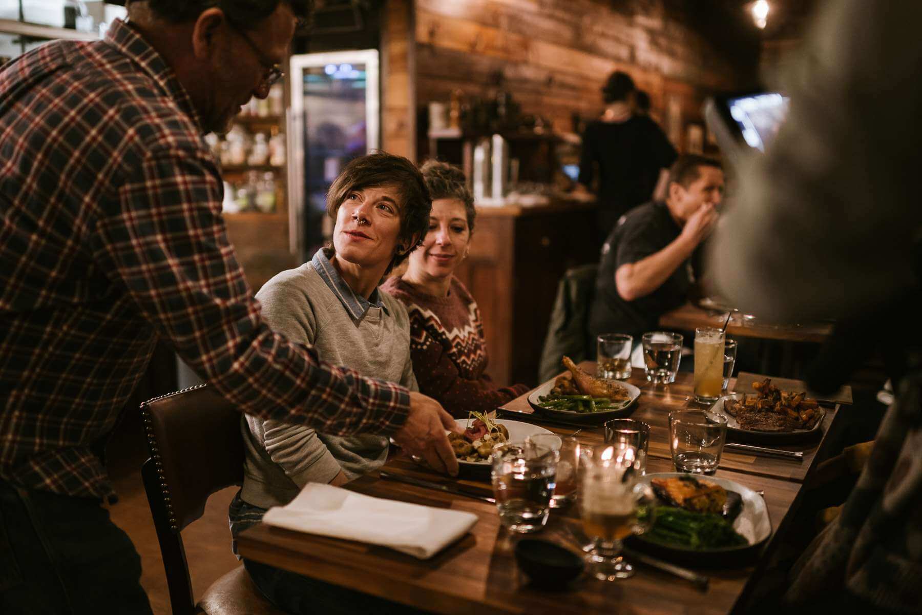 Winter in the Cascade Mountains: A man presents a plate of food to a table of diners.